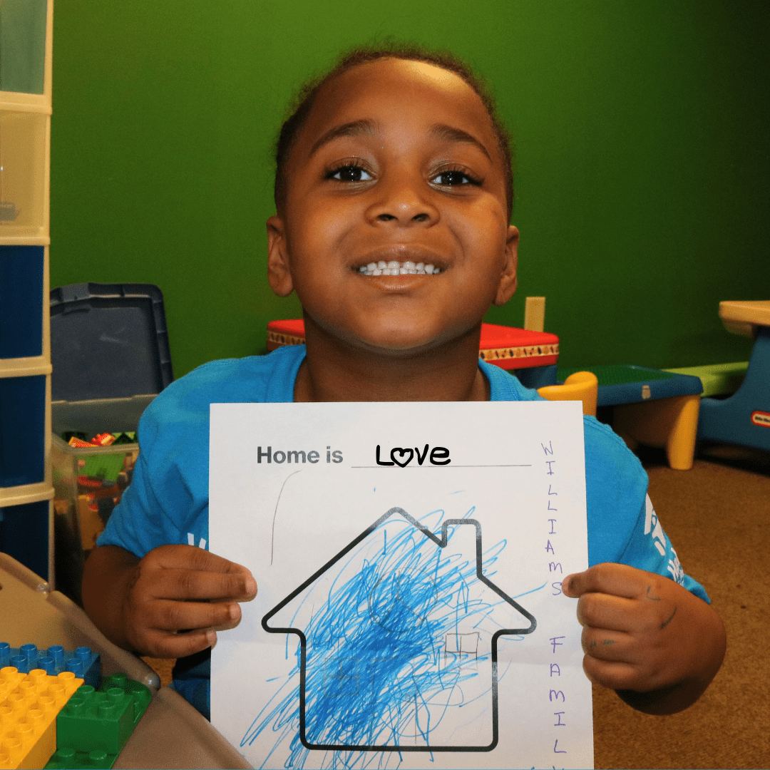 Bishop smiling while holding up hand drawn picture of future home